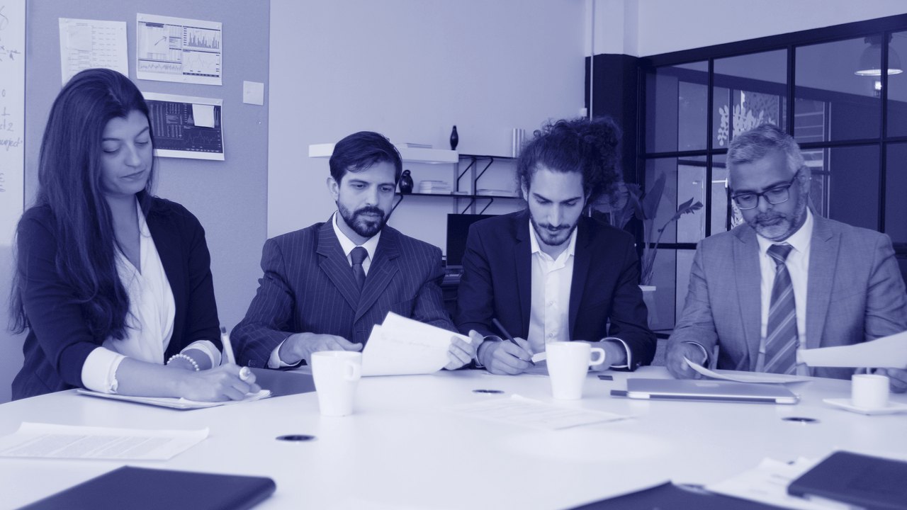 Cuatro profesionales revisando documentación jurídica alrededor de una mesa de reuniones